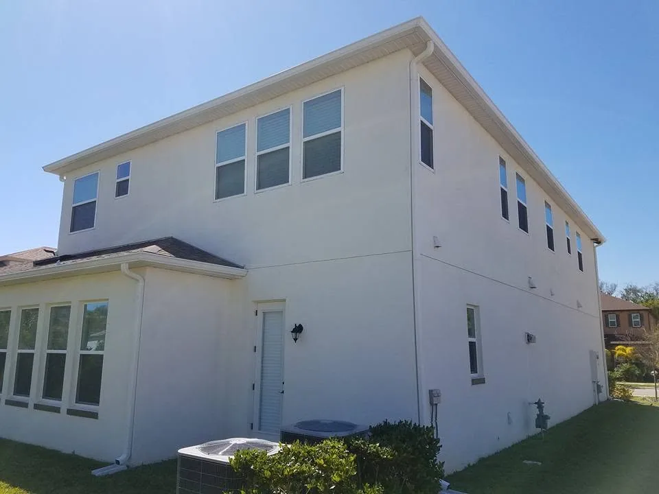 Rear corner white stucco two story ac units seamless gutters, Sanford